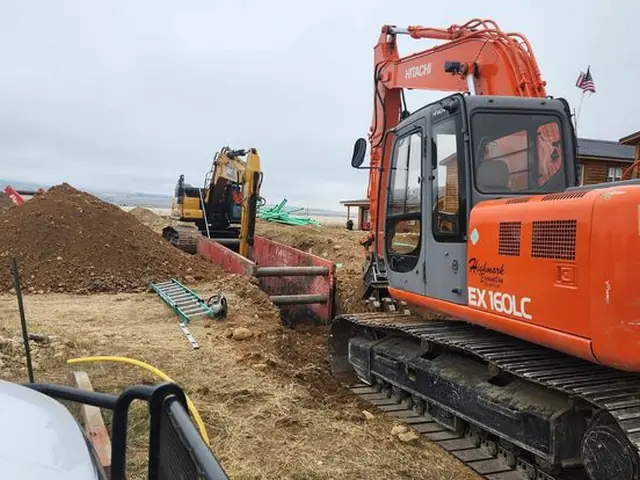 Two excavators working on an underground utility trench