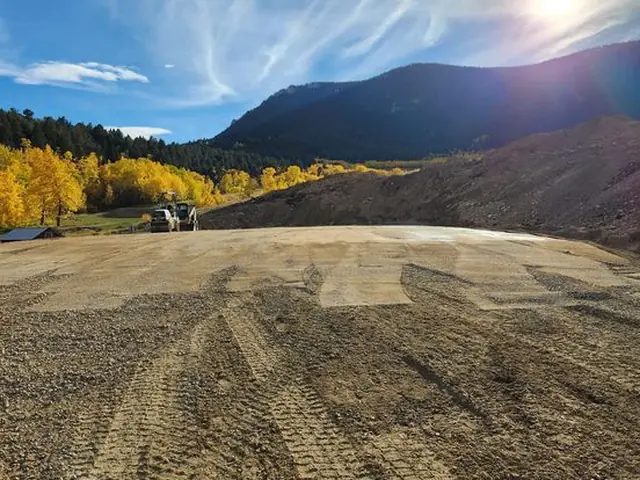 Graded construction pad with Montana mountains and fall aspens