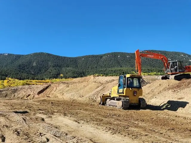 Excavator and dozer completing mass earthwork in a Montana valley