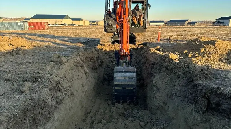 Excavator performing water and sewer utility trenching in Montana